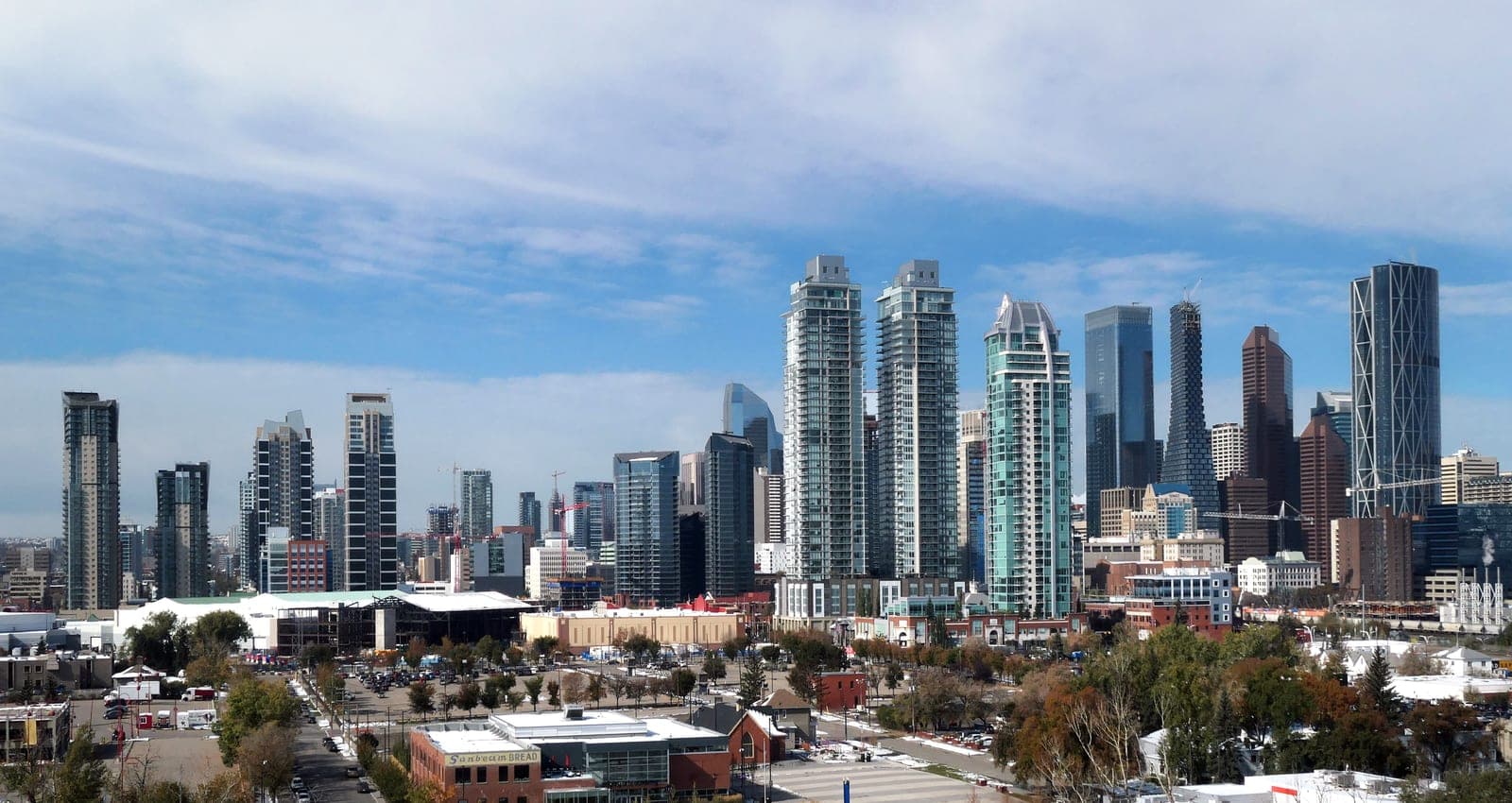 Calgary's downtown skyline seen from a distance, with the Bow River and green space in the foreground.
