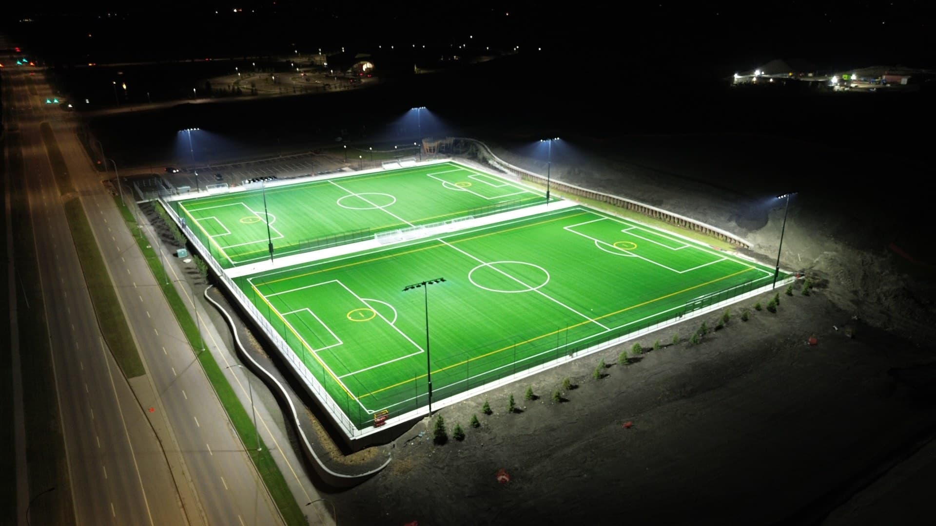 Two artificial turf fields illuminated at night at Rocky Ridge Athletic Park in Calgary.