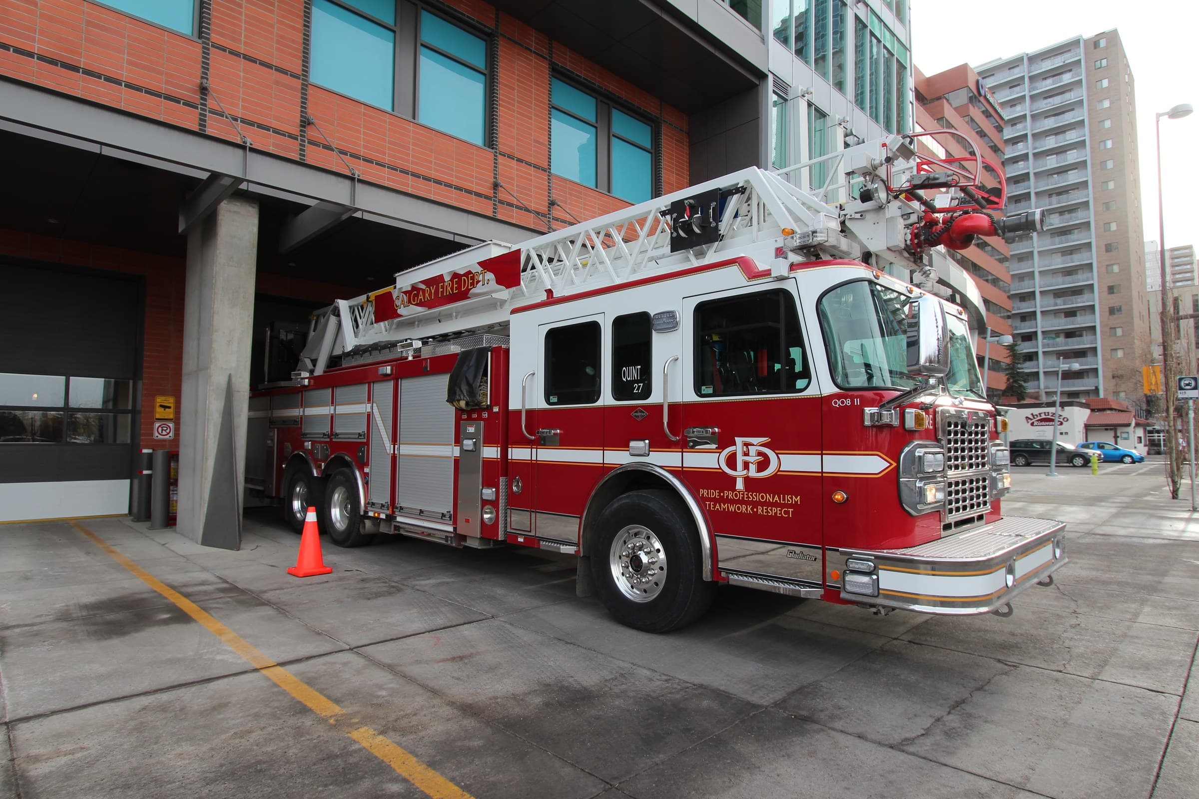 Calgary Fire Department aerial ladder truck parked at an open fire-station bay.
